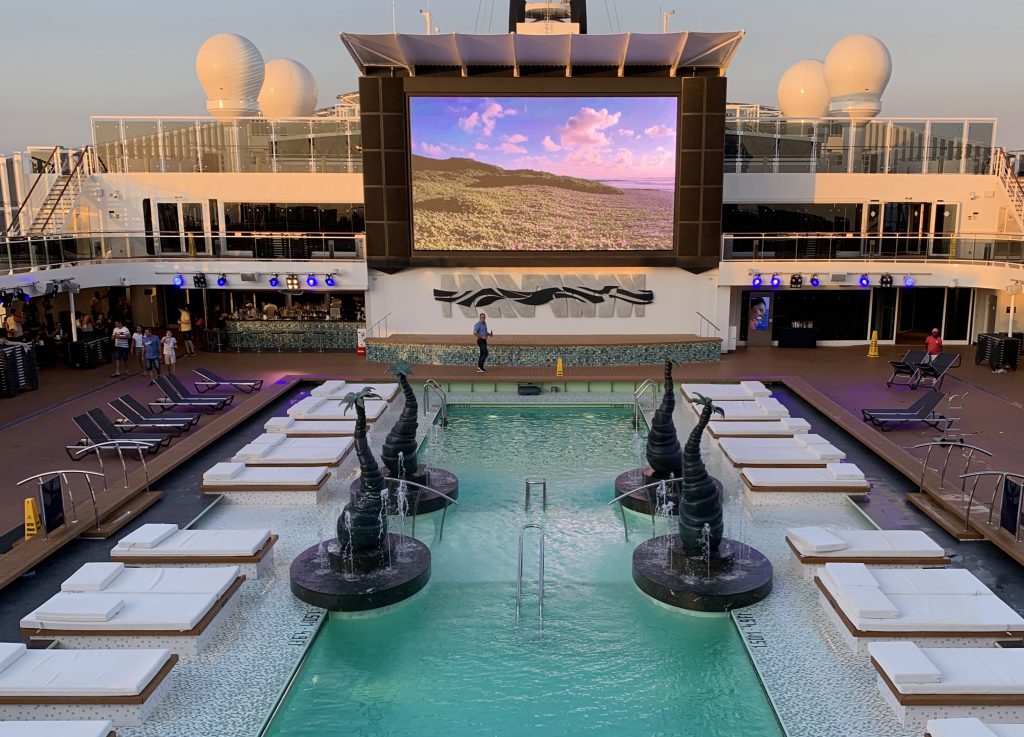 Pooldeck der MSC Bellissima mit Loungeliegen und großer Videoleinwand